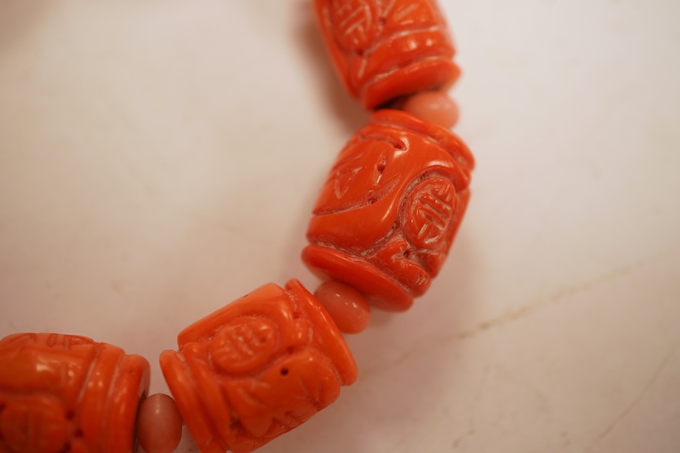 Two coral bead necklaces, one composed of large cylindrical coral beads, approximately 2.5-3.5cm each, total length 49cm; and a bracelet composed of carved coral beads spaced by smaller pink coral beads, on an elasticate